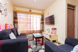 - un salon avec deux canapés bleus et une table dans l'établissement Homely Queen Bed Apartment Near Nairobi CBD, à Nairobi