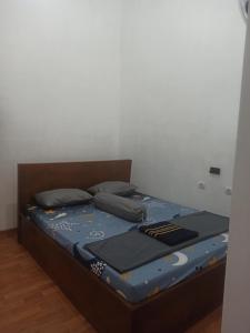 a bed with blue sheets and pillows in a room at Ador 46 Homestay Syariah & Kost in Mergan