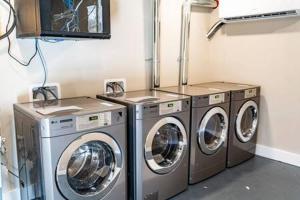 a laundry room with three washing machines and a tv at Modern and Convenient Norwood Knox in Knoxville