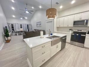 a kitchen with a sink and a stove top oven at Emerald Coast Retreat 2 4person golf carts large swim spa included in Mexico Beach
