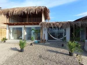 a house with a thatched roof and palm trees at Kanaloa Casa de Playa frente al mar, Los Órganos in Los Órganos