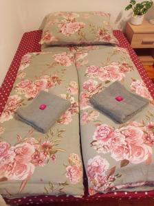 a bed with two pillows on it with pink roses at Apartmán Eva in Liptovský Svätý Peter