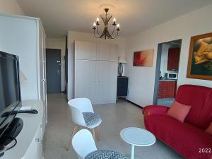 ein Wohnzimmer mit einem roten Sofa und weißen Stühlen in der Unterkunft Appartement Argelès-sur-Mer, 1 pièce, 4 personnes - FR-1-776-39 in Argelès-sur-Mer