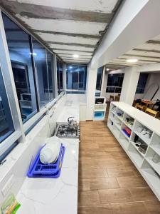 uma cozinha em plano aberto com armários brancos e janelas em Mariandes Hostel em Huaraz