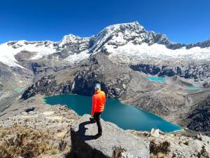 Ein Mann steht auf einem Felsen mit Blick auf einen Berg in der Unterkunft Mariandes Hostel in Huaraz