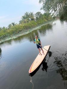 Un homme sur une planche de paddle dans l'eau dans l'établissement Rai Lung Tui Homestay, à Prachuap Khiri Khan