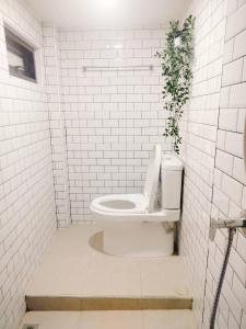 a white bathroom with a toilet with a plant on it at Gamin house hatyai city in Ban Khlong Toei (1)