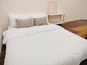 a bed with white sheets and pillows in a room at Gamin house hatyai city in Ban Khlong Toei (1)