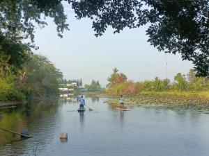 two people are paddleboarding down a river at Rai Lung Tui Homestay in Prachuap Khiri Khan
