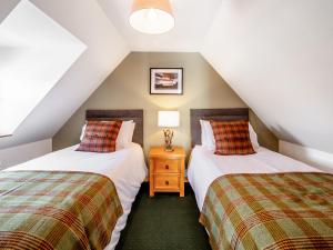 two twin beds in a attic room with two lamps at The Old Library in Brora