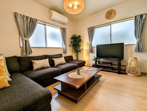 a living room with a couch and a tv at Tsukiyume Kan - House with Parking, 10Mins to USJ, Tennoji, Namba in Osaka
