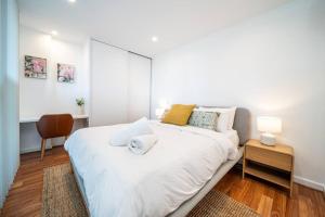 a white bedroom with a large white bed and a desk at Wattle on Morphett - Central CBD WiFi in Adelaide +17 photos