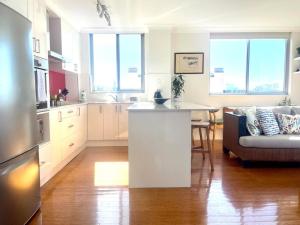 a kitchen and living room with a couch and a table at Perfect Randwick Escape -2Bdrm-Parking - Walk To Hospital & Shops in Sydney