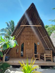 ein kleines Bambushaus mit einer Bank davor in der Unterkunft Na Wa Cottages in Panglao