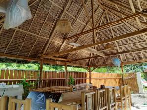 a patio with a table and chairs under a straw umbrella at Na Wa Cottages in Panglao Island
