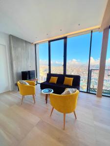 ein Wohnzimmer mit einem schwarzen Sofa und gelben Stühlen in der Unterkunft Edificio IQON, Piso 28, La Mejor vista de Quito in Quito