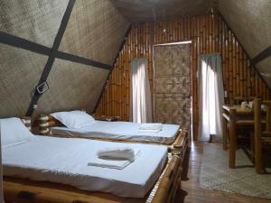 1 dormitorio con 2 camas, mesa y ventana en Na Wa Cottages, en Panglao