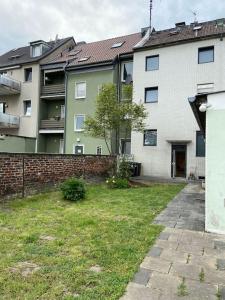 um edifício de apartamentos e um quintal com uma cerca de tijolos em Charmante Gartenwohnung mit privatem großen Garten em Colônia