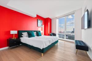 1 dormitorio con pared roja, cama y ventana en Tallest Penthouse in NJ with Wraparound Balcony, en Hoboken