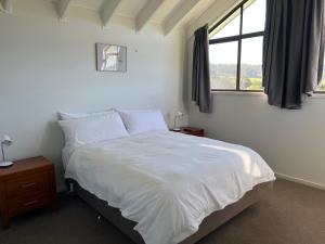 um quarto com uma cama branca e uma janela em Black Bream Point Cabins em Narooma