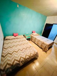 2 camas en una habitación con paredes azules en Casa Buganbilia en San Sebastián Etla