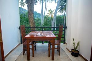 ゴールにあるD2 Villa Unawatunaの木製テーブルと椅子付きのバルコニーから眺めの良い景色を楽しめます。