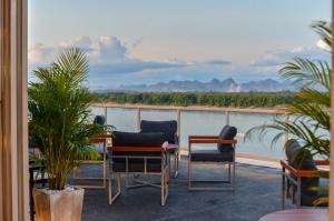 balcón con sillas y vistas al agua en Blu Hotel en Nakhon Phanom