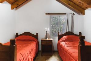 - une chambre avec 2 lits avec des draps rouges et une fenêtre dans l'établissement Rivendell Bungalows Bariloche, à San Carlos de Bariloche