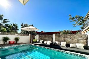 a swimming pool with a couch and an umbrella at Baja House in Todos Santos