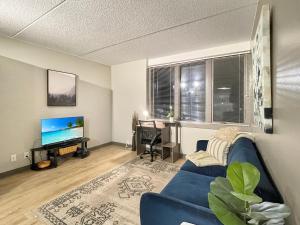 sala de estar con sofá azul y TV en Downtown 1br By Steps From Wells Free Parking en Des Moines