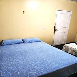 Cama azul en habitación con puerta en Hotel & Residencial Marajoara, en Breves