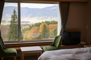 a bedroom with a large window and a bed and chairs at HOKURYUKO HOTEL North NAGANO in Iiyama