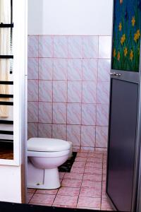 a bathroom with a toilet and a pink tiled wall at Sanasuma Hotel in Hambantota