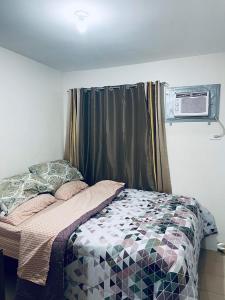 a bedroom with a bed and a window with a air conditioner at One Spatial Iloilo Two Bedroom Condominium Unit with Pool and Gym in Iloilo City