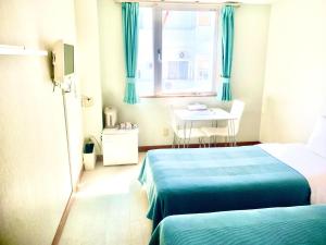 Zimmer mit 2 Betten, einem Tisch und einem Fenster in der Unterkunft Hotel Happy Holiday Ishigakijima - Vacation STAY 04127v in Ishigaki-jima