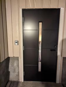 a black door in a building with a mirror at Koselig leilighet nær bussholdeplass og natur. in Tromsø