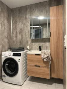 uma casa de banho com uma máquina de lavar roupa e um lavatório em Koselig leilighet nær bussholdeplass og natur. em Tromsø