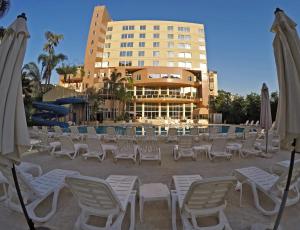 eine Gruppe von Stühlen und Sonnenschirmen vor einem Hotel in der Unterkunft Cosmopolitan Hotel in Beirut
