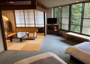 a room with a bed and a tv and some windows at Yukyo no Hibiki Yusai in Minamioguni