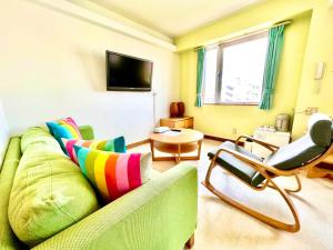 ein Wohnzimmer mit einer grünen Couch und einem Stuhl in der Unterkunft Hotel Happy Holiday Ishigakijima - Vacation STAY 04026v in Ishigaki-jima