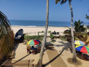 a beach with chairs and umbrellas and a boat at Tripsea Beach Villa in Alleppey