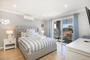 a white bedroom with a bed and a balcony at Bluewater Jervis Bay - Pet Friendly with Spa in Callala Beach