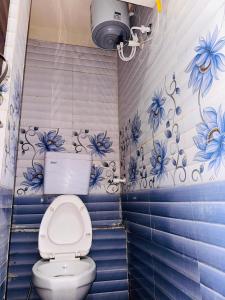 a bathroom with a toilet with blue flowers on the wall at Tiwari G Shridhara Hotel in Ujjain