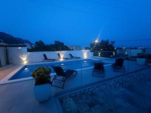 un patio con sillas y una piscina por la noche en Holiday house Doris with pool, garden and view, en Kaštela