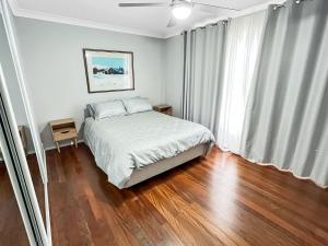 Schlafzimmer mit einem Bett und Holzboden in der Unterkunft Mirror Bay in Laurieton