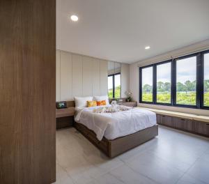 a bedroom with a large bed and large windows at Verdant Bali Sekar Sari in Denpasar