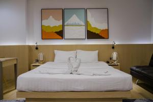 a bedroom with a white bed with four paintings at Sakura Sky Residence in Bangkok