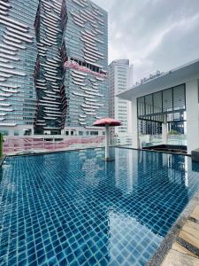 a pool with a red umbrella and tall buildings at Reizz Residence By D'Amour in Kuala Lumpur