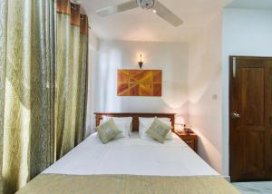 a bedroom with a bed and a ceiling fan at Kerawalapitiya Resort in Mahabage