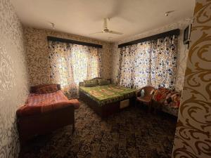 a room with a bed and a couch and curtains at Hotel Kashmir Heaven in Srinagar